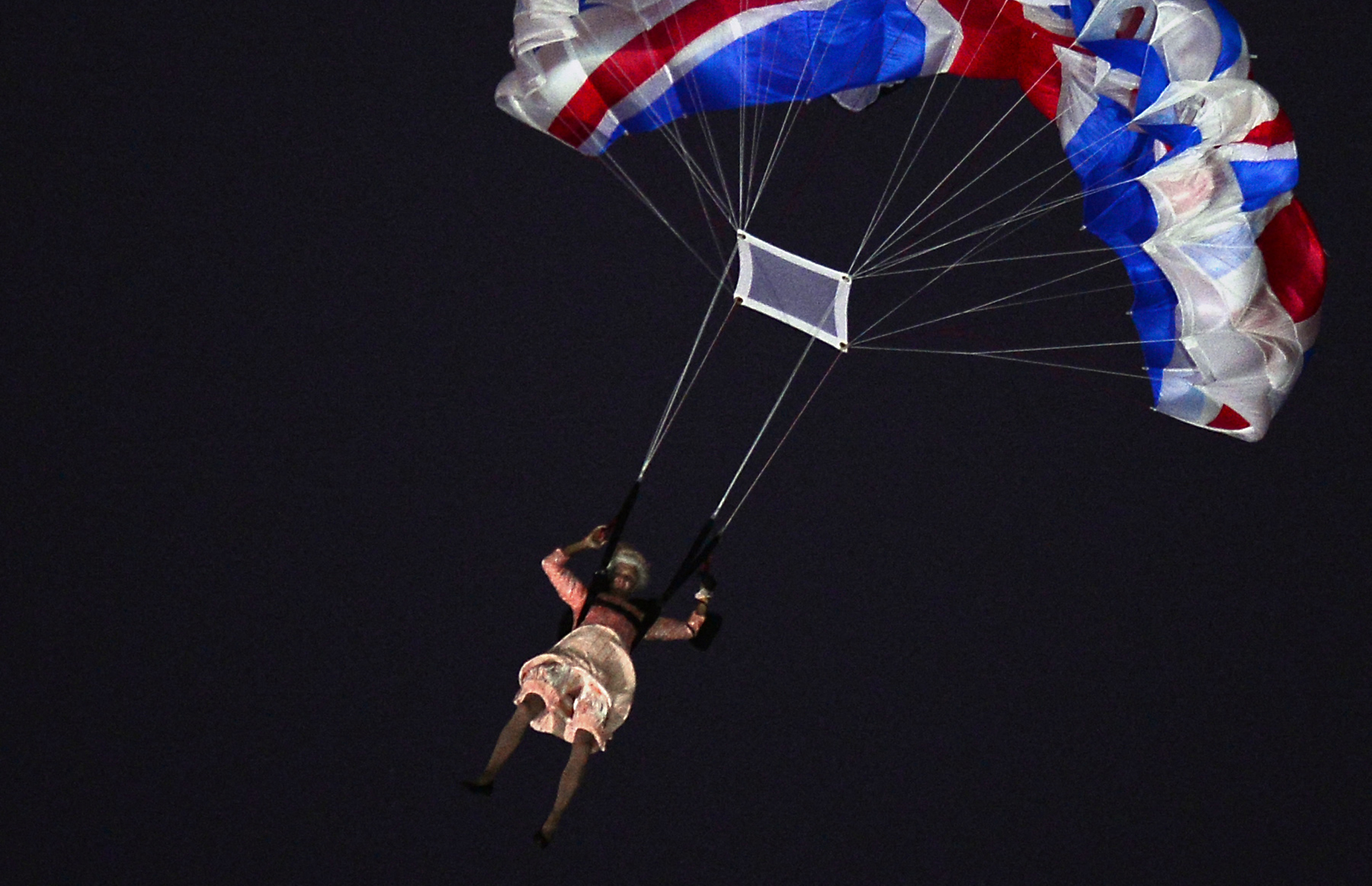 TOPSHOT - An actor dressed to resemble Britain&amp;amp;apos;s Queen Elizabeth II parachutes into the stadium during the opening ceremony of the London 2012 Olympic Games at the Olympic Stadium in London on July 27, 2012. AFP PHOTO / OLIVIER MORIN (Photo by Olivier MORIN / AFP) (Photo by OLIVIER MORIN/AFP via Getty Images)