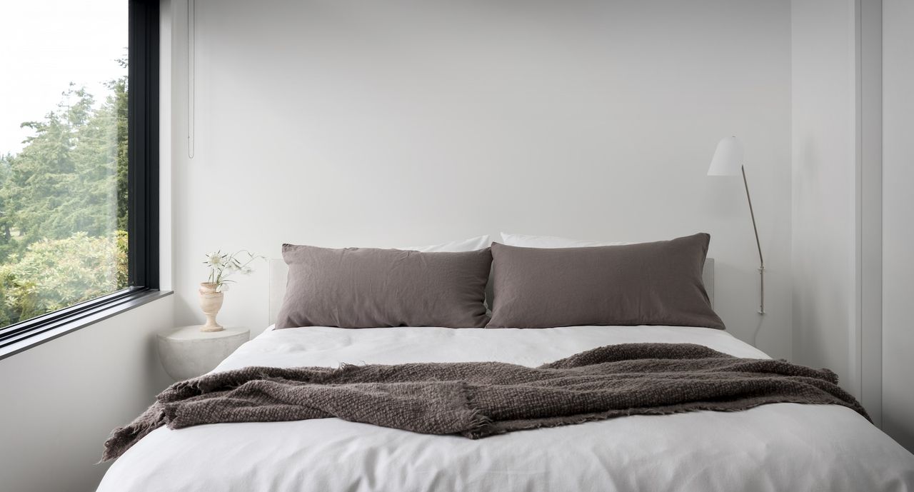 close up image of the head of a bed with two grey rectangular cushions on white sheets