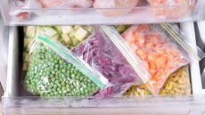 An image of an open freezer drawer that's got bags of neatly organized foods inside it