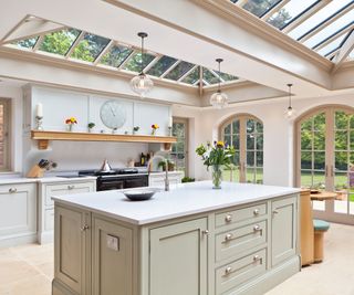 orangery kitchen extension with double rooflights and arched doors at end, large kitchen island with light sage green doors