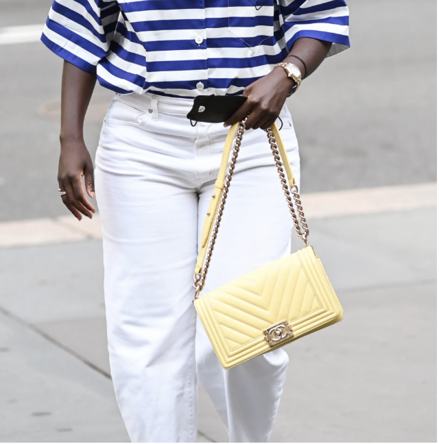 nikki ogunnaike wearing a striped shirt, white pants, and a yellow bag