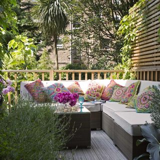 Sunny wooden decking area, L shaped sofa, colourful cushions, Moroccan Moorish style garden