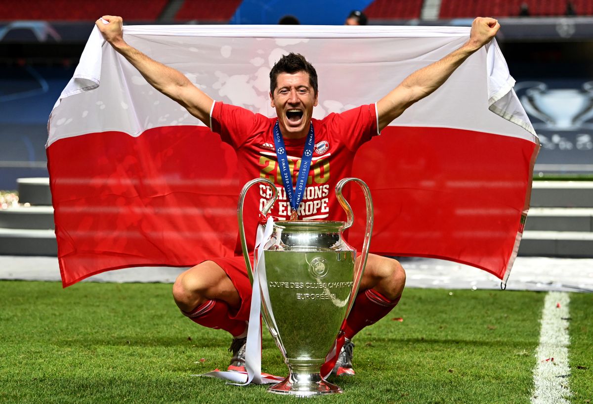 Robert Lewandowski poses with the Champions League trophy and the Polish flag after Bayern Munich&#039;s win over Paris Saint-Germain in the 2020 final in Lisbon.