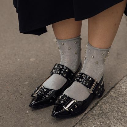 Woman wearing black slingback flats with gray socks. 