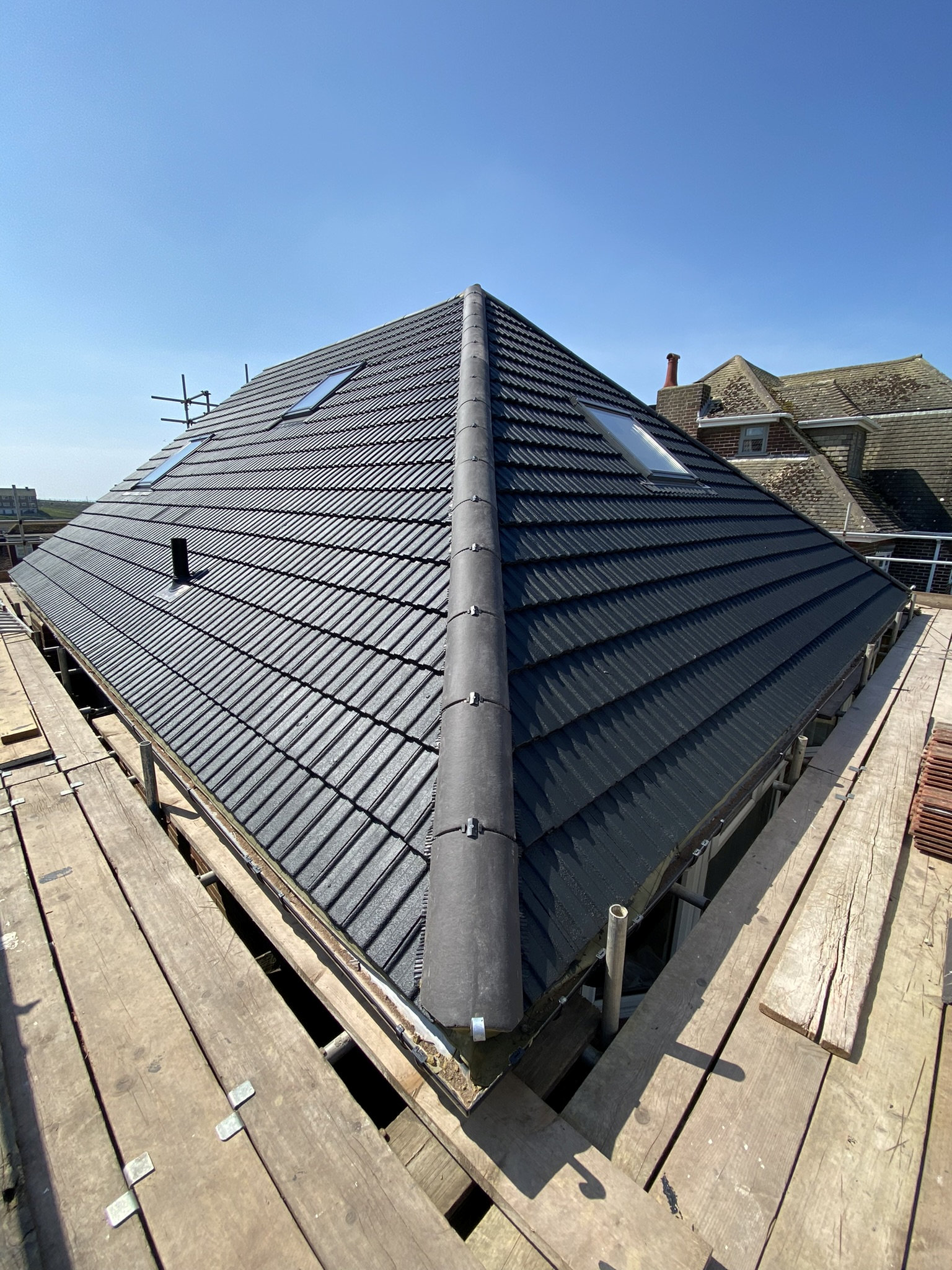 The finished roof with painted black roof tiles and scaffolding around the base