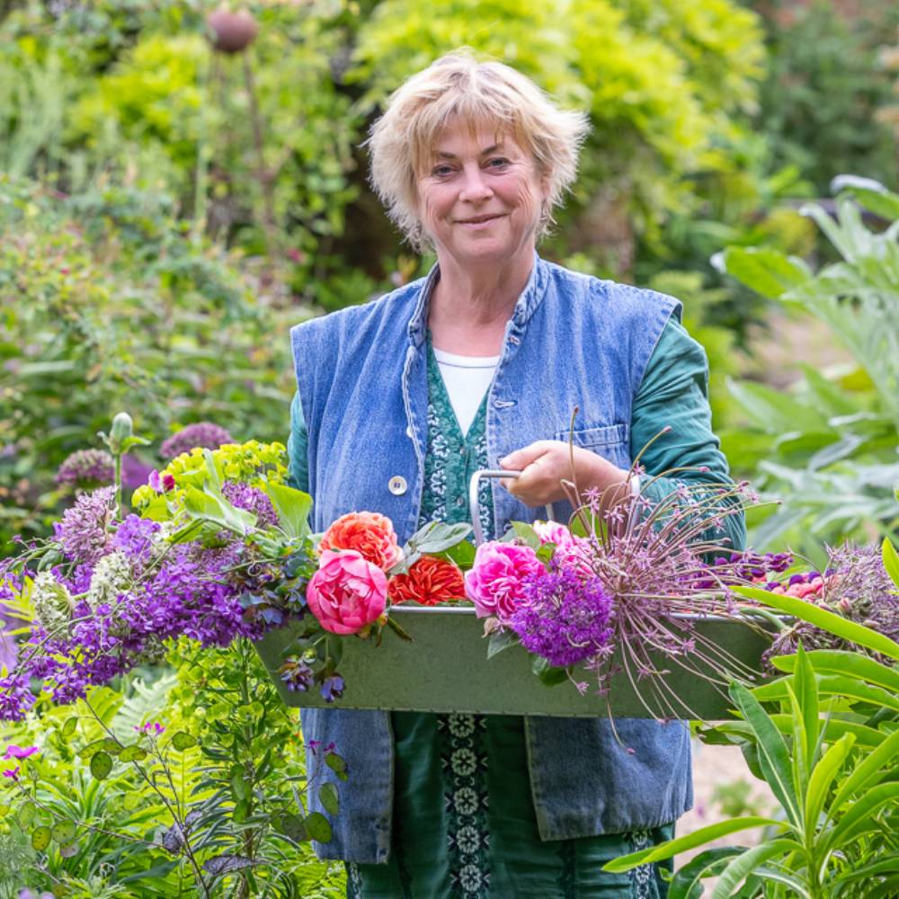 Sarah Raven in a garden holding a trug