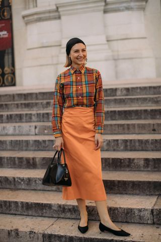 Woman in plaid shirt and orange skirt