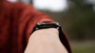 OnePlus Watch rundt et håndledd, fotografert fra siden så knappene synes.