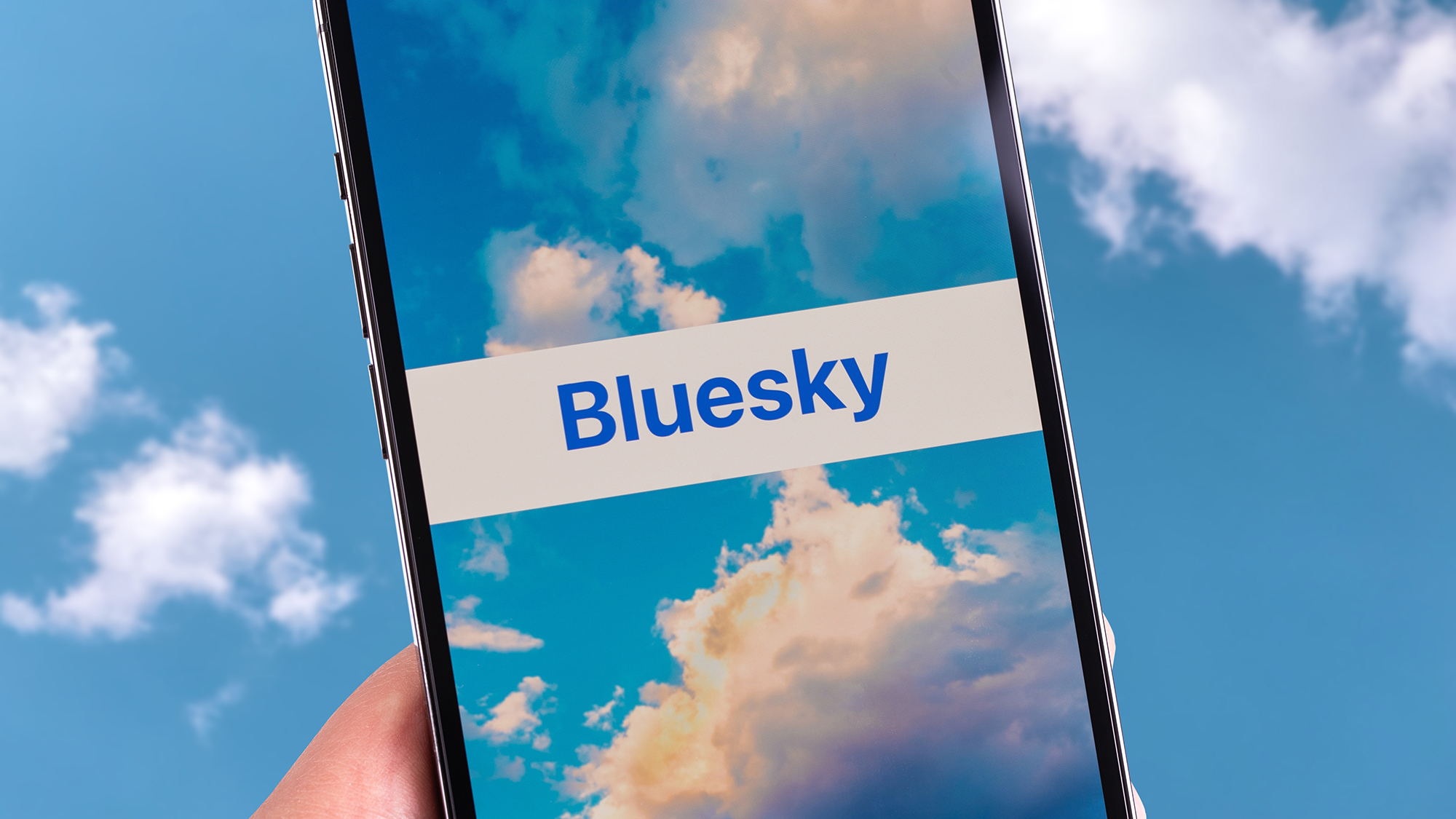 Das Logo der Bluesky-App, umgeben von blauem Himmel, auf dem Bluesky-Anmeldebildschirm.