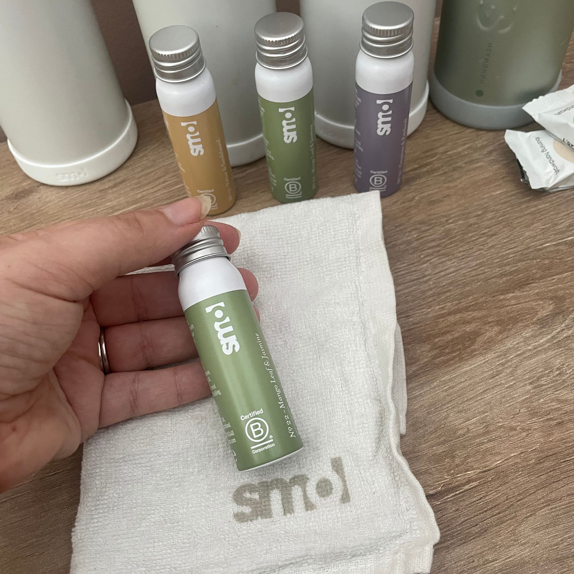 Hand holding smol cleaning product bottle in front of more bottles and on top of a white cleaning cloth