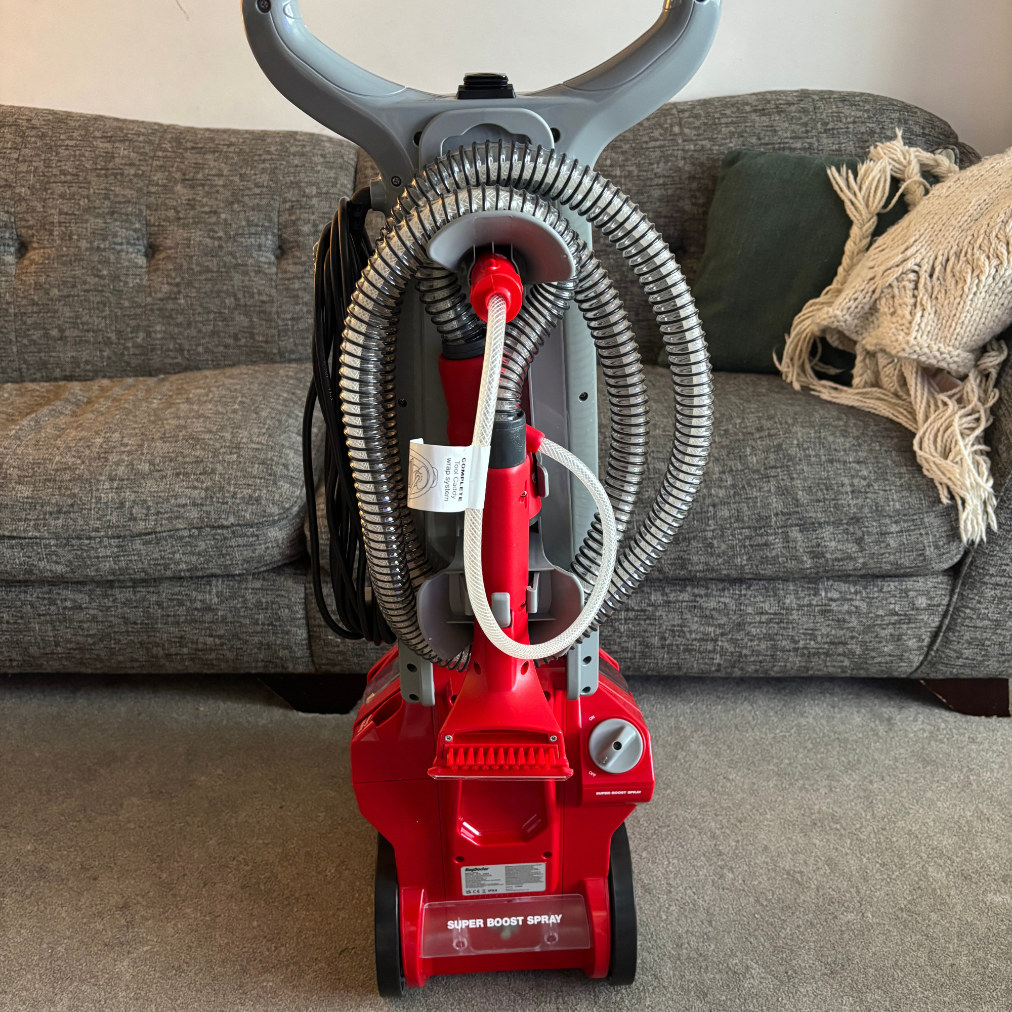 Rug Doctor Deep Upright Carpet Cleaner stood upright on carpet in front of grey sofa
