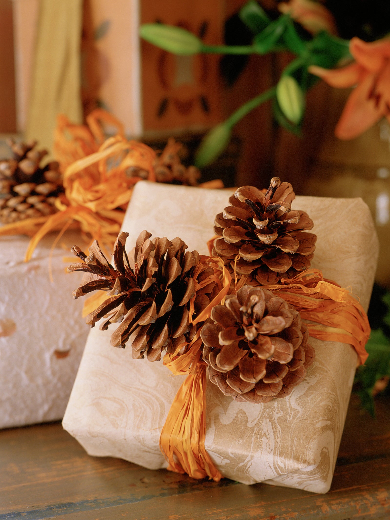 Traditional fragrant Christmas decorations: rustic gift wrapped present with marbled paper, pinecones and orange raffia ribbon