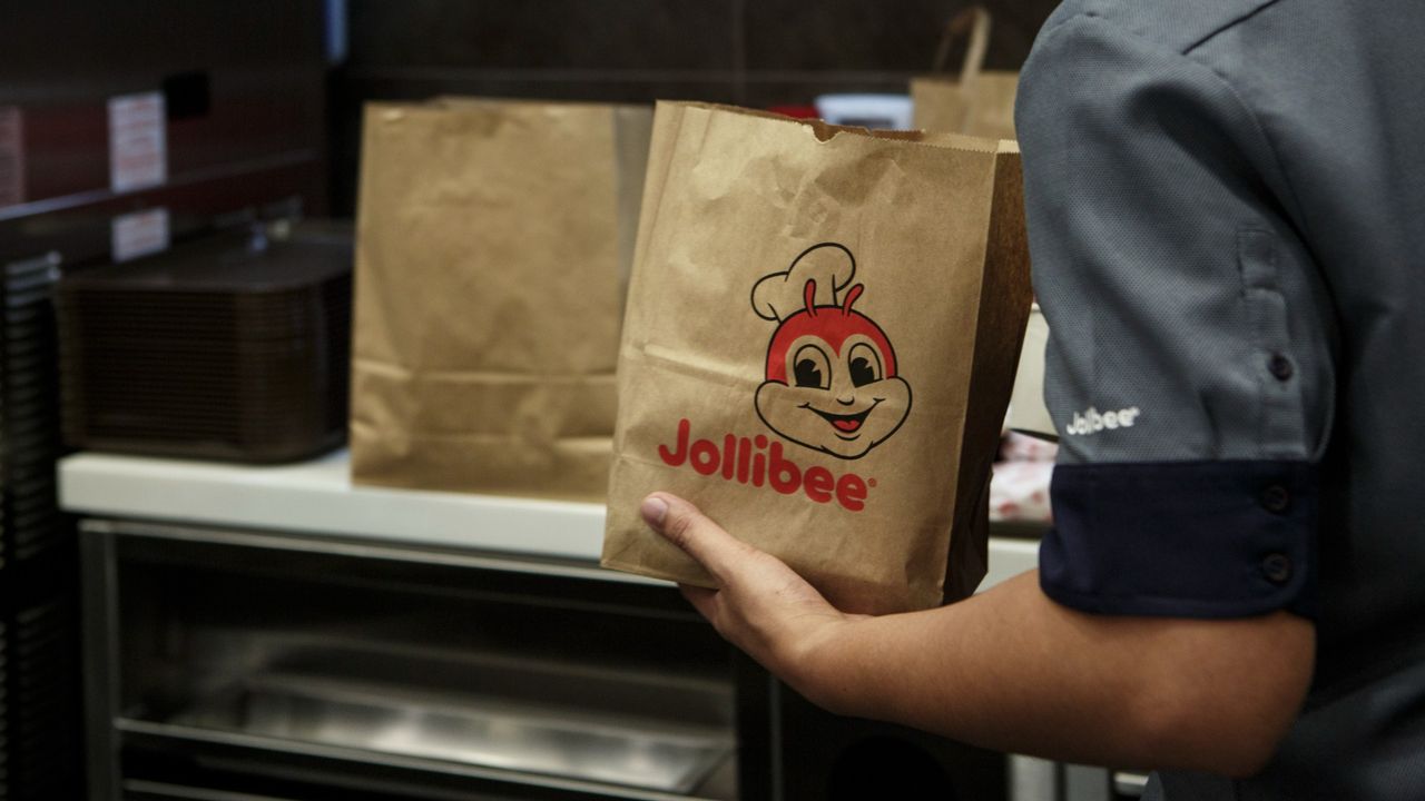 A fast food worker places food into a Jollibee bag.