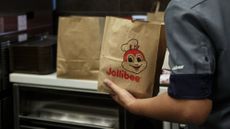 A fast food worker places food into a Jollibee bag.