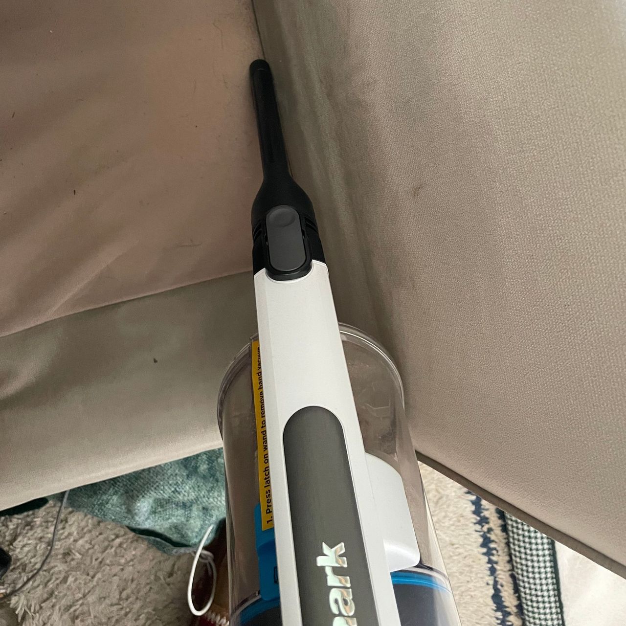 Using the crevice tool of the Shark PowerPro Pet Cordless Stick Vacuum to clean the side of a sofa