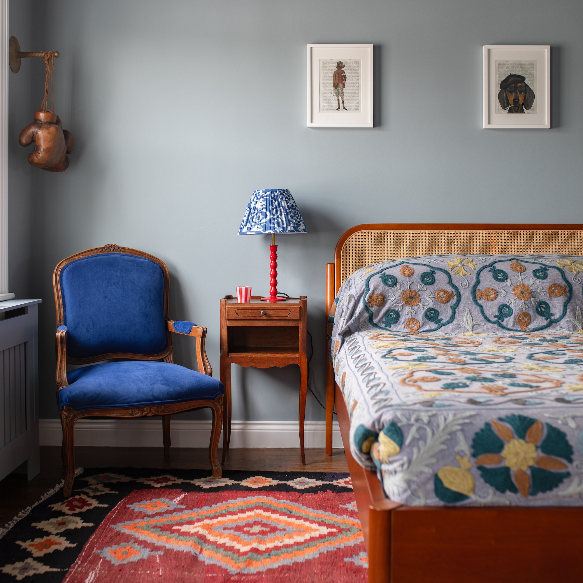 bedroom with double bed with rattan headboard and antique carver chair upholstered in blue velevet