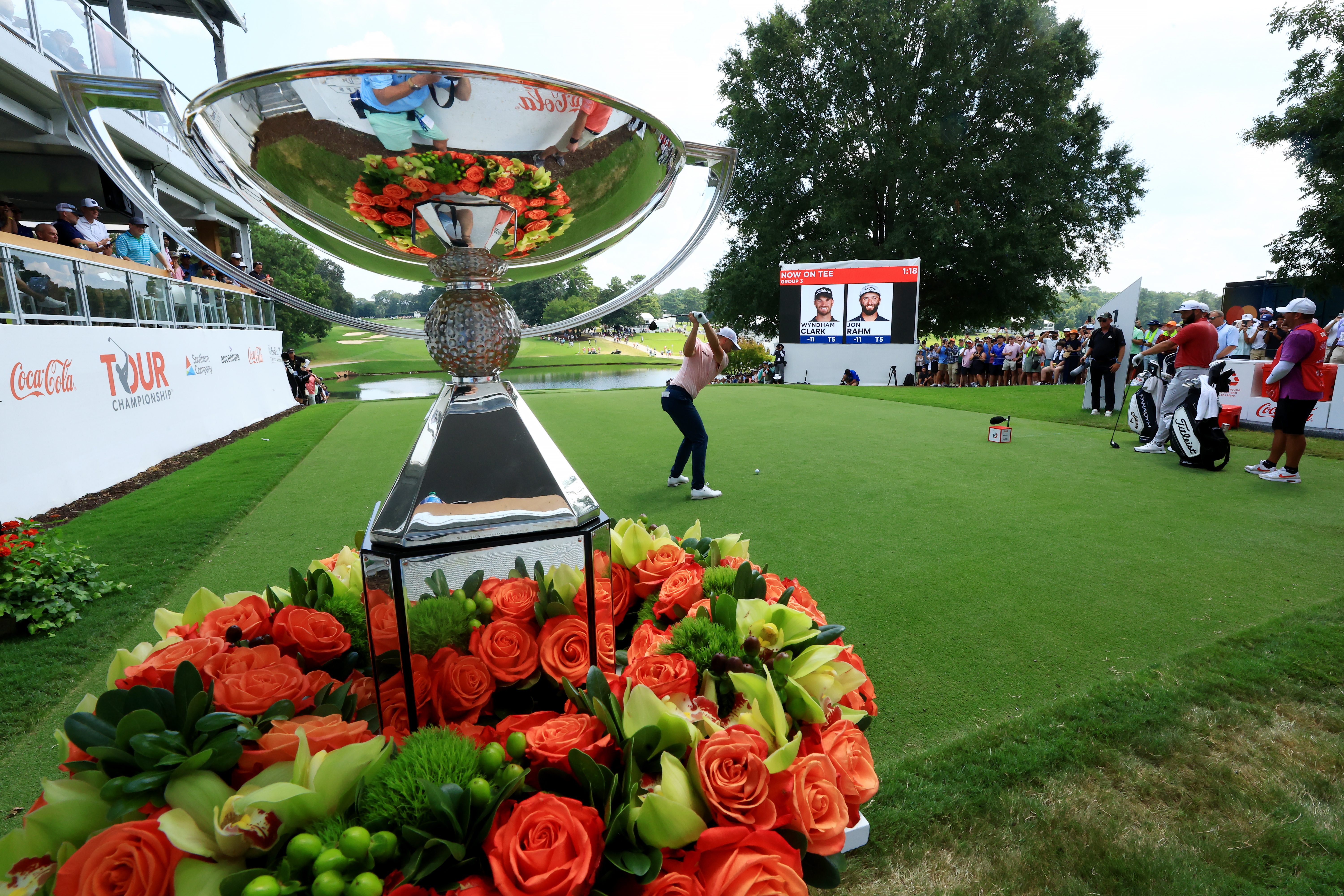 Wyndham Clark at the top of his backswing, with the FedEx Cup trophy behind him