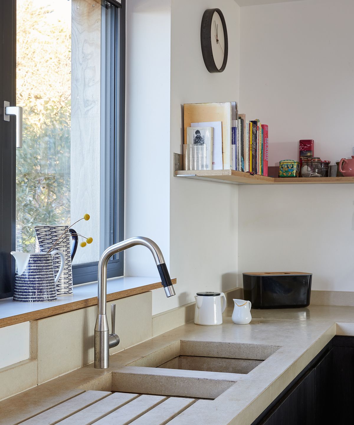 A kitchen sink with stanless steel taps and bookshelves
