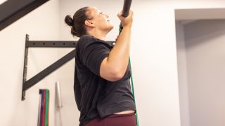 Woman performs a chin-up with the assistance of a resistance band