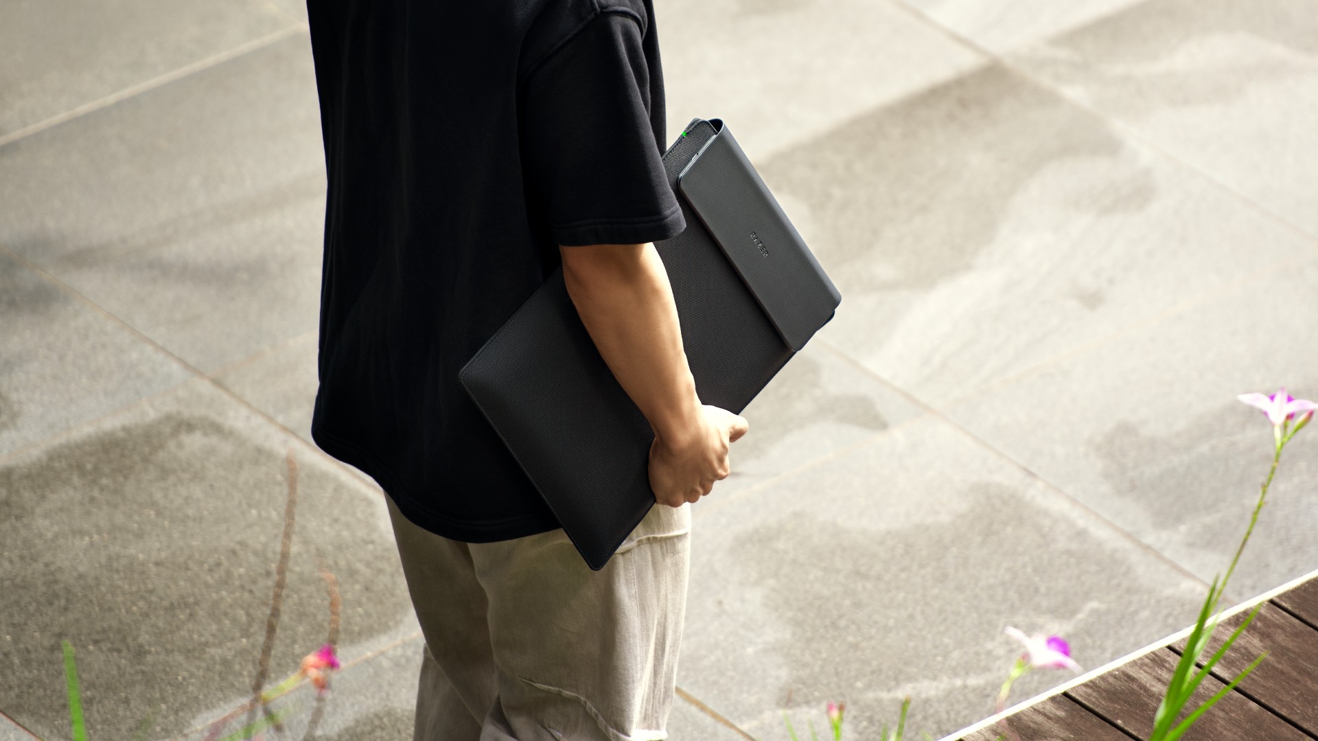 A person carrying a Razer Laptop Sleeve on a sidewalk
