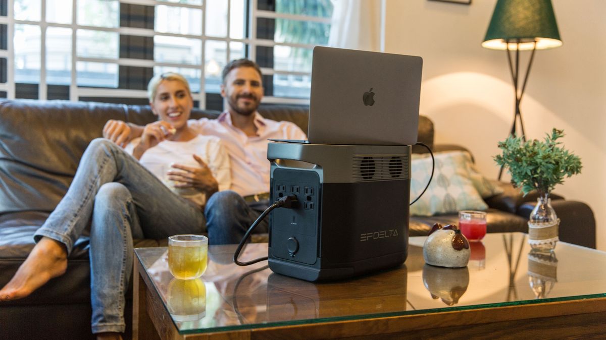 Ecoflow delta on a table with a laptop plugged in as a couple watches in the background