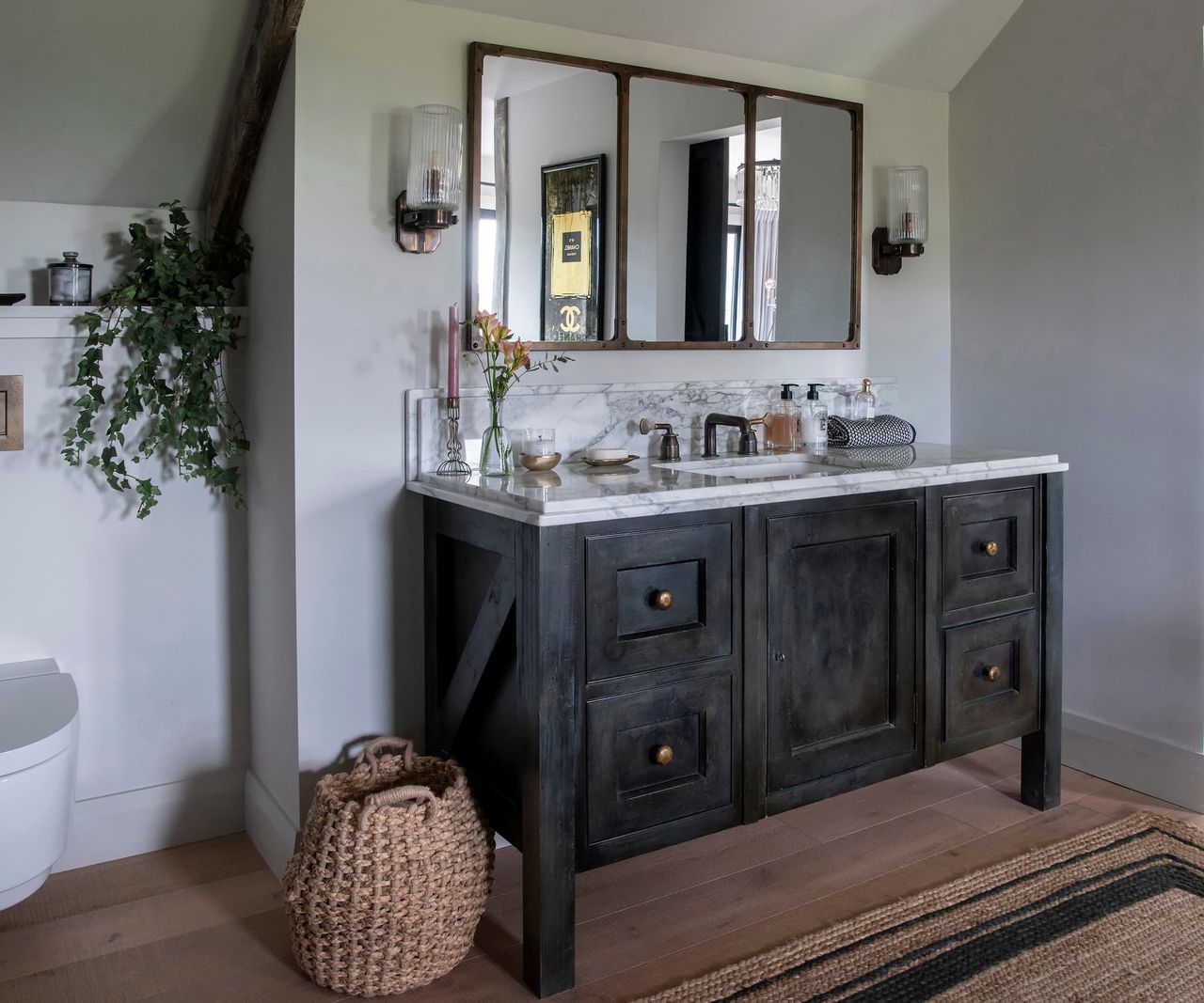 A bathroom with a wall toilet and a sink in the shape of a cupboard