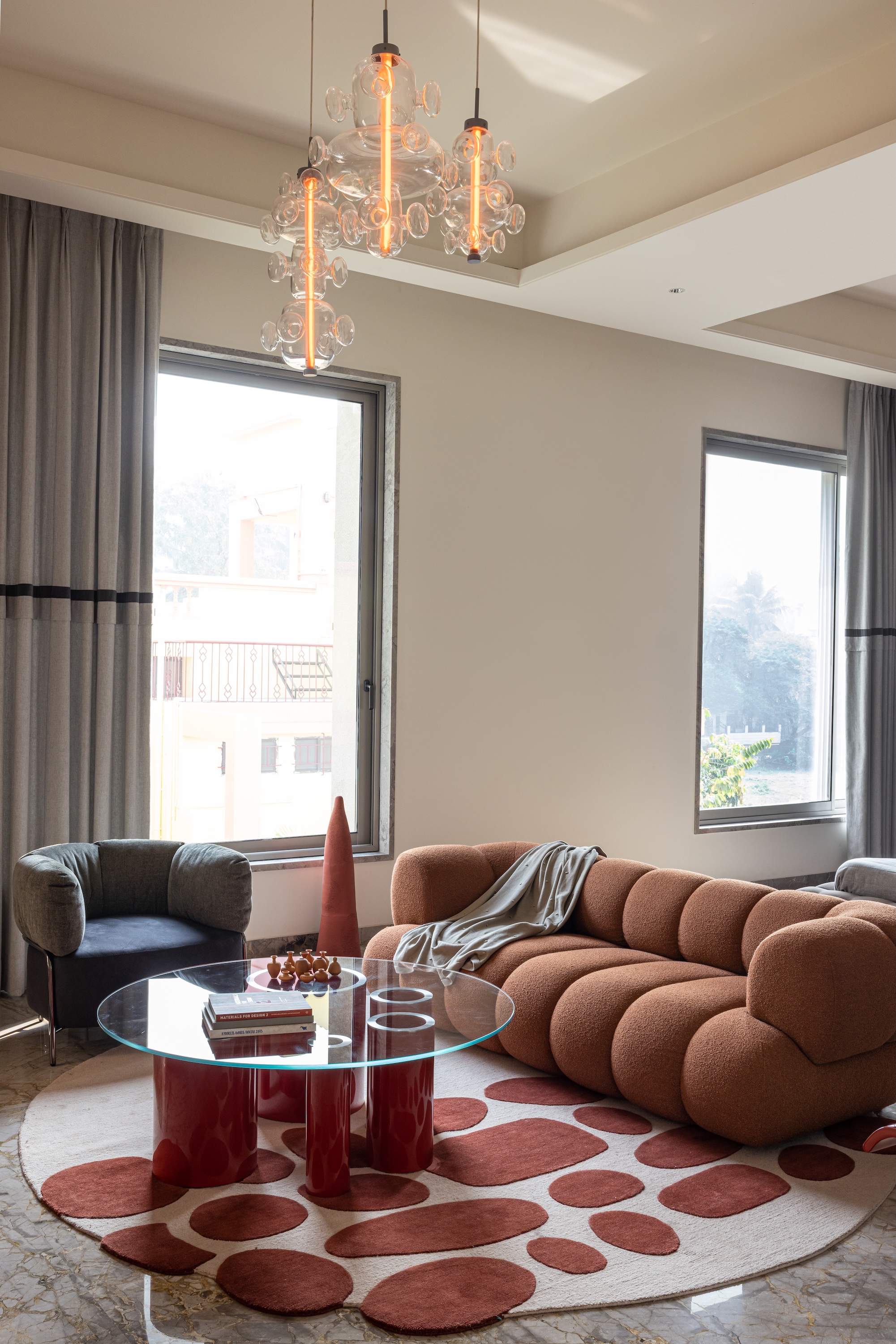 living room with contemporary rust-coloured sofa, glass coffee table and spotty rug