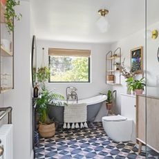 bathroom with geometric floor tiles, white and grey bathtub and plants