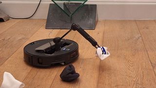 Roborock Saros Z70 robot vacuum picking up a sock with its pincer arm