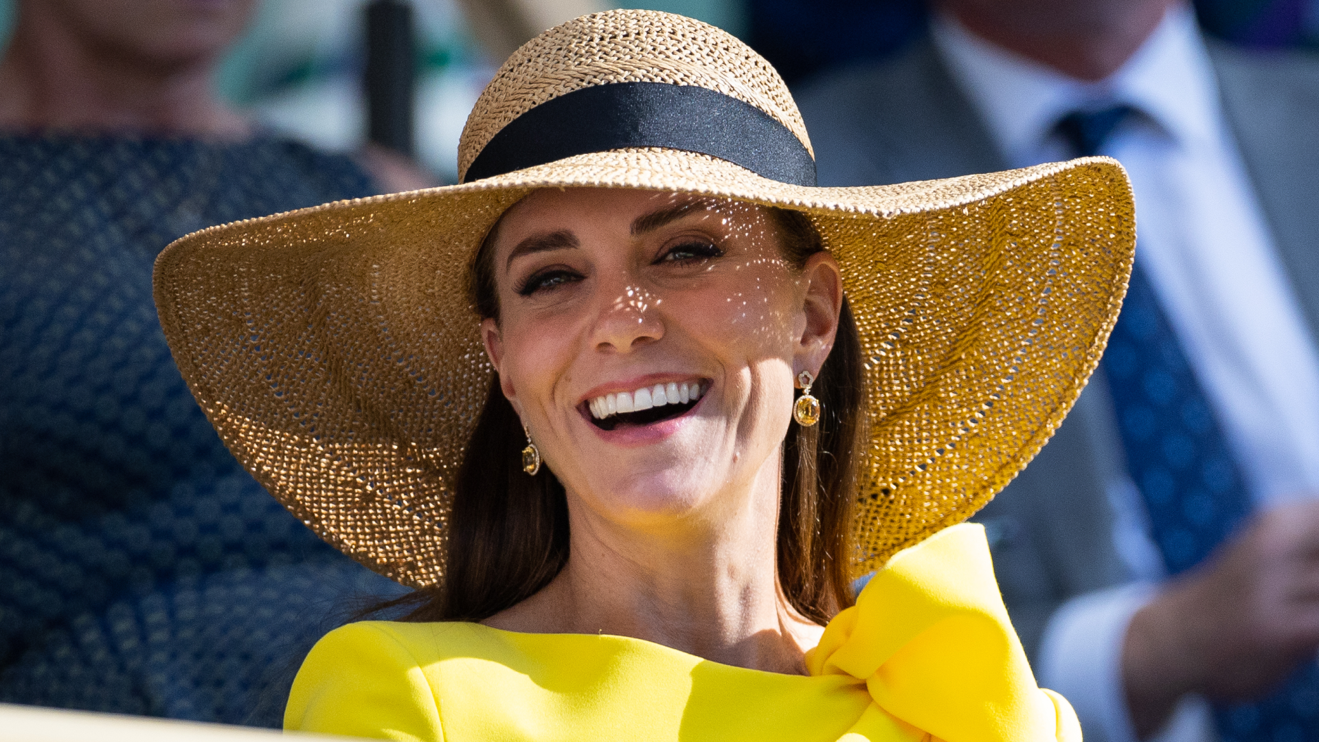Kate Middleton wearing a yellow dress and sun hat smiling