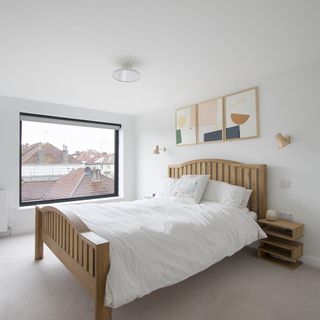 master bedroom with bed white walls and pictures on wall