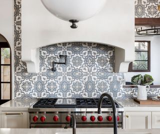 blue patterned kitchen tiles with a white range cooker hood and stainless steel range