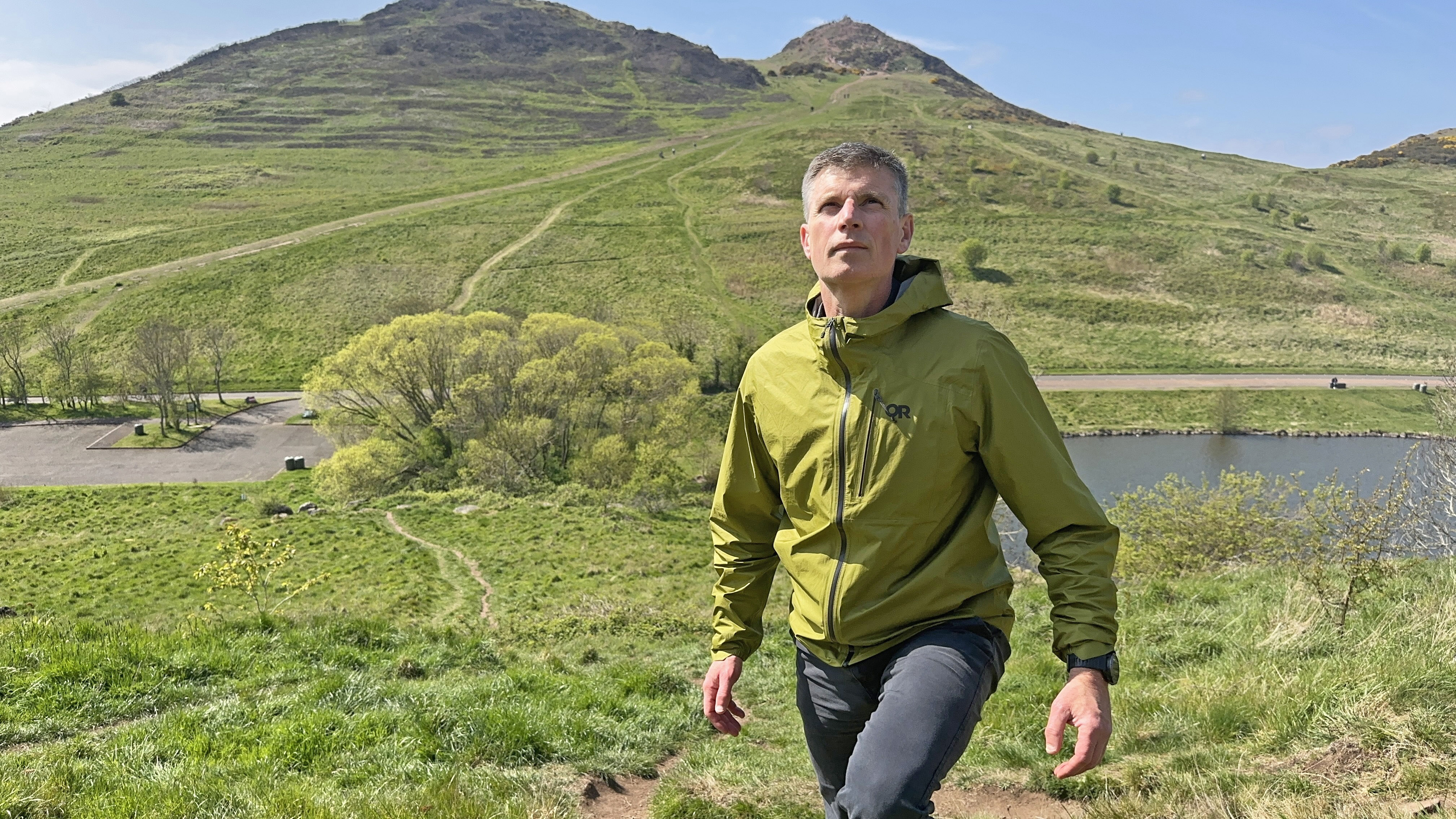 Hiker wearing the Outdoor Research Helium UL jacket in the hills