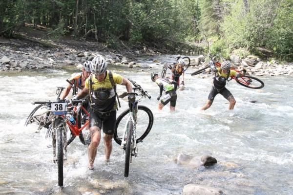 The TransRockies ideal of honour among competitors is displayed by Kris Sneddon (38, left) who carries a bike for a Belgian rider from Team Granville/ Trustteam who is still midstream.