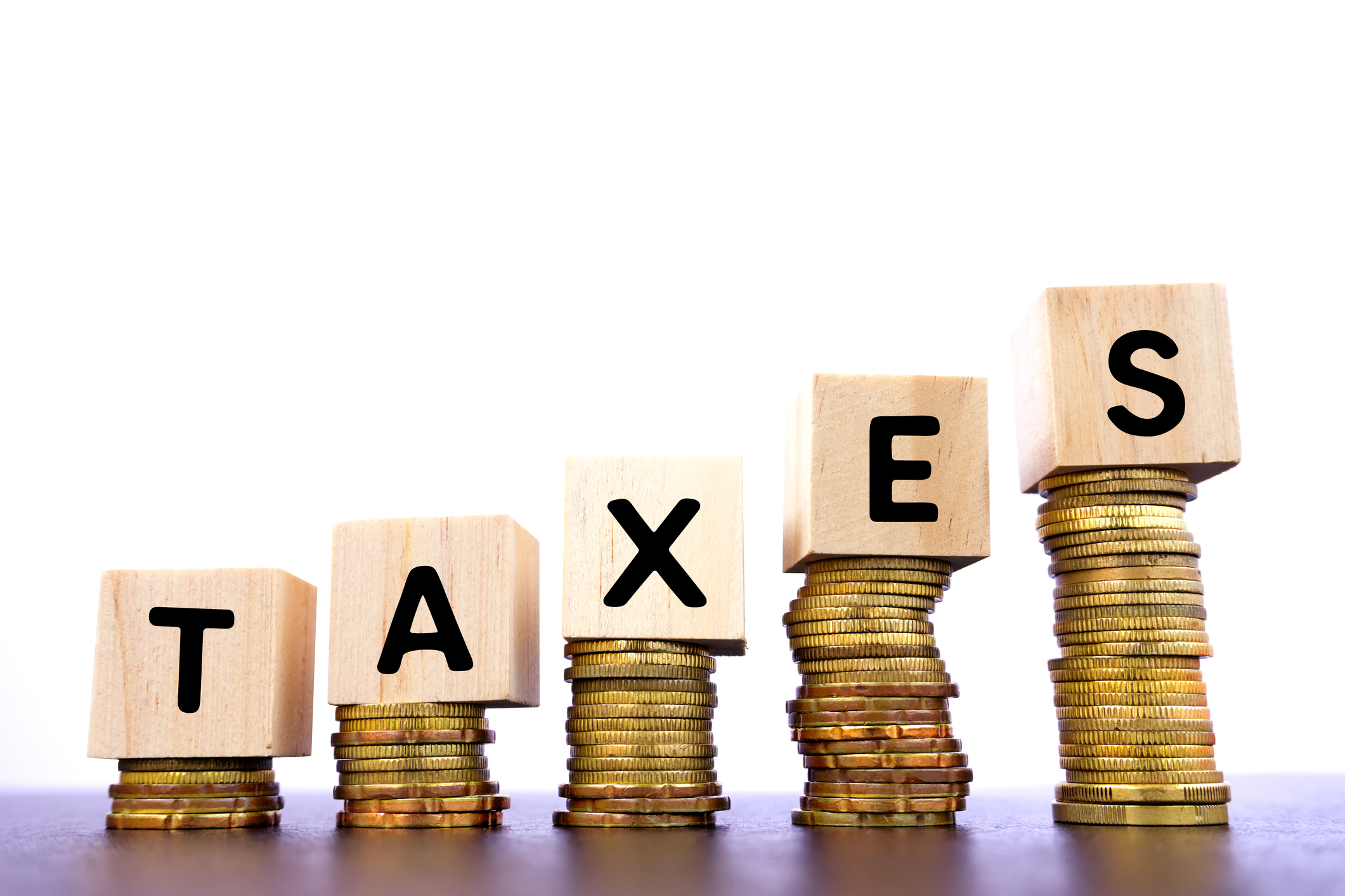 Taxes spelled out in blocks rising on higher piles of coins