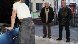 Phil stares at the ground while Nigel and Harry talk in the garage