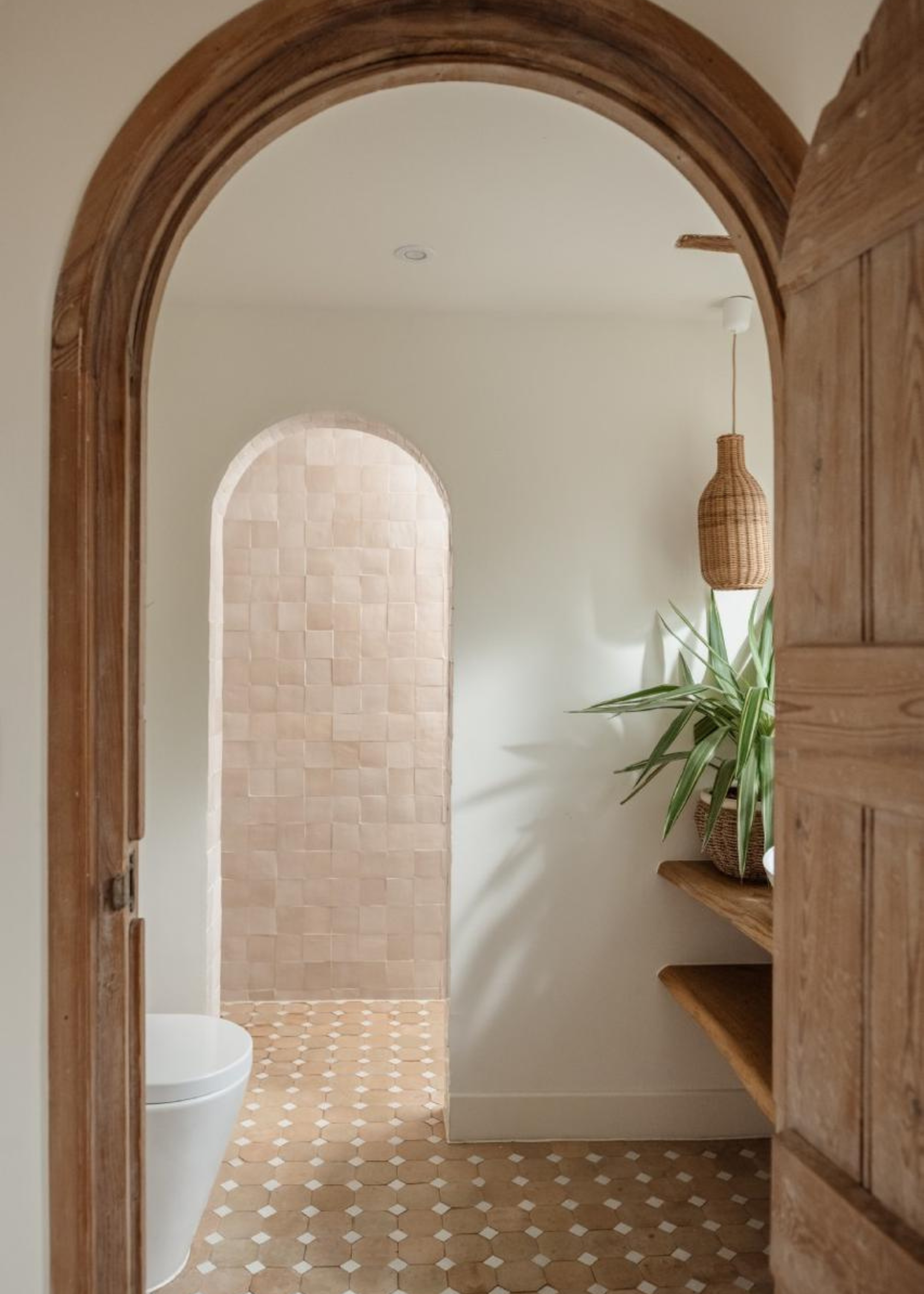 a doorway in to a beautiful bathroom with zellige tiles and raw ceramic floor tiles