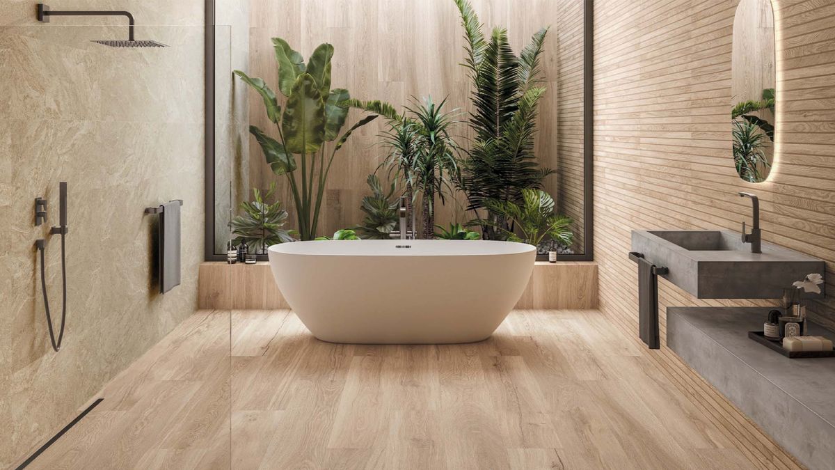 bathroom with wood effect floor and wall tiles, indoor garden to rear of room with white freestanding bath, walk in shower and concrete moulded sink and countertop