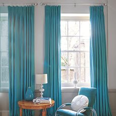 room with white wall and blue curtains and blue arm chair