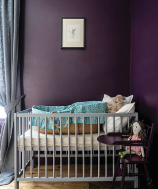 nursery room with dark purple walls and light gray cot