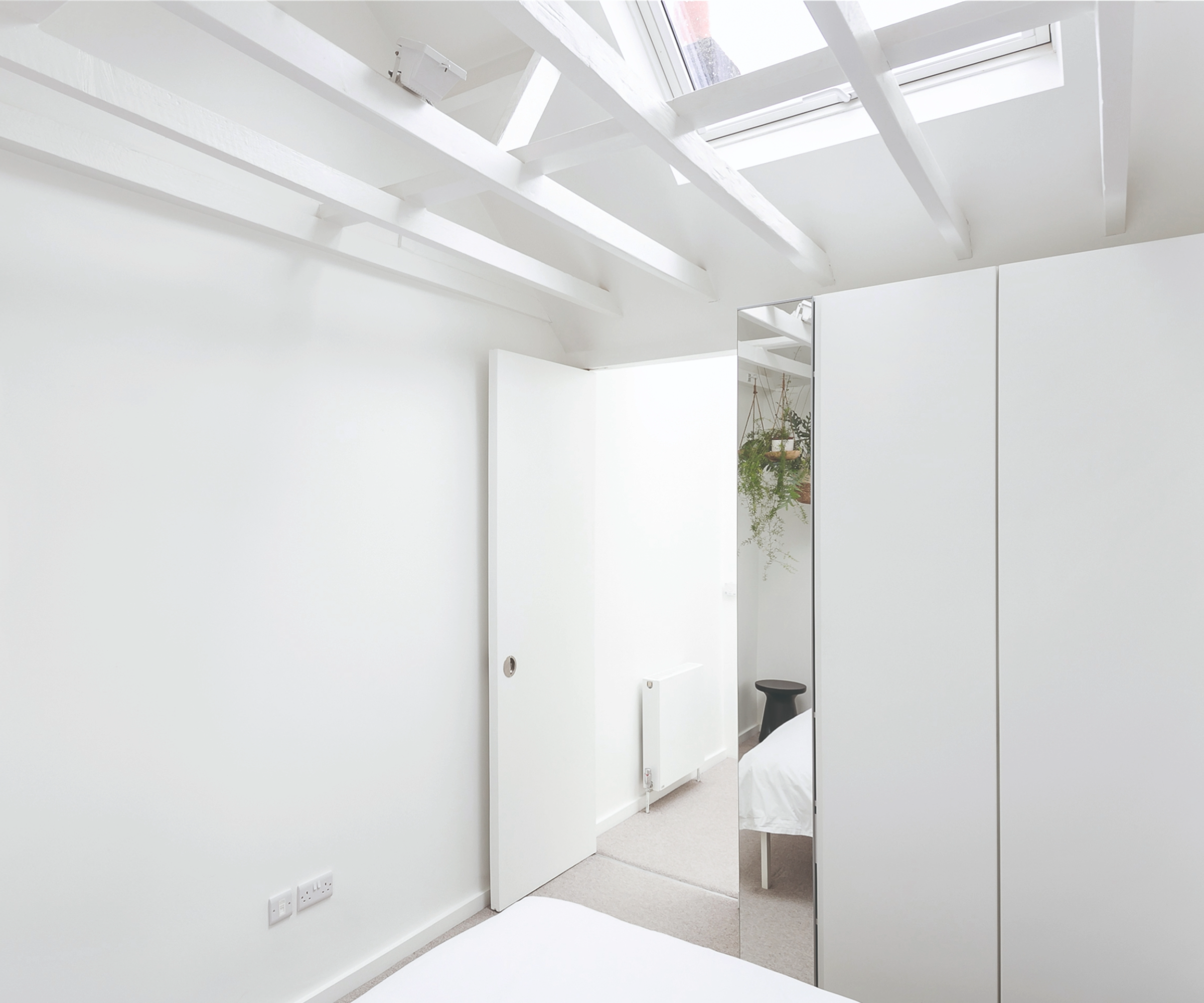 View of the bedroom facing the white wardrobe and door