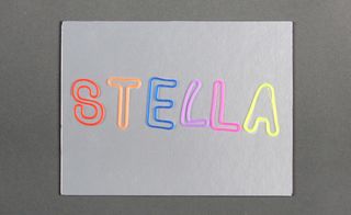 View of Stella McCartney's silver invitation featuring colourful letters pictured against a grey background