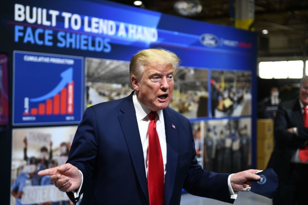 President Trump tours a Ford factory while holding a mask.