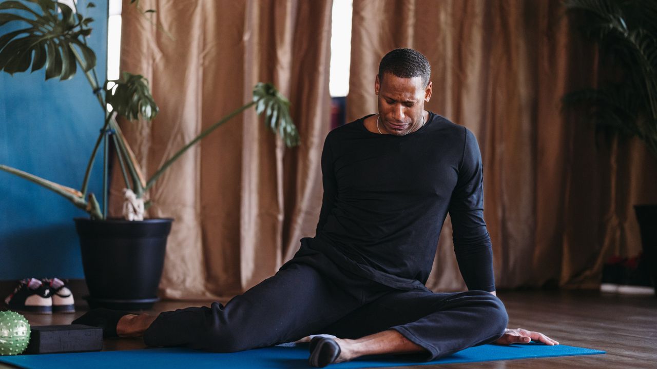 A man performing 90/90 hip wipers on the floor at home