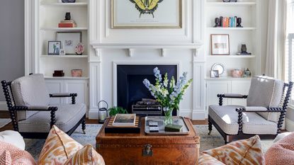 white living room with open shelving, fireplace and bobbin armchairs