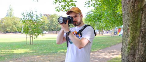 A man wearing the BlackRapid Sport Breathe Left and Right in a park with camera raised to eye-level