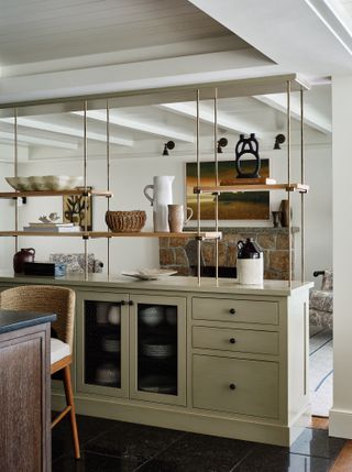 A kitchen with open shelving build above the kitchen cabinets displaying decorative objects