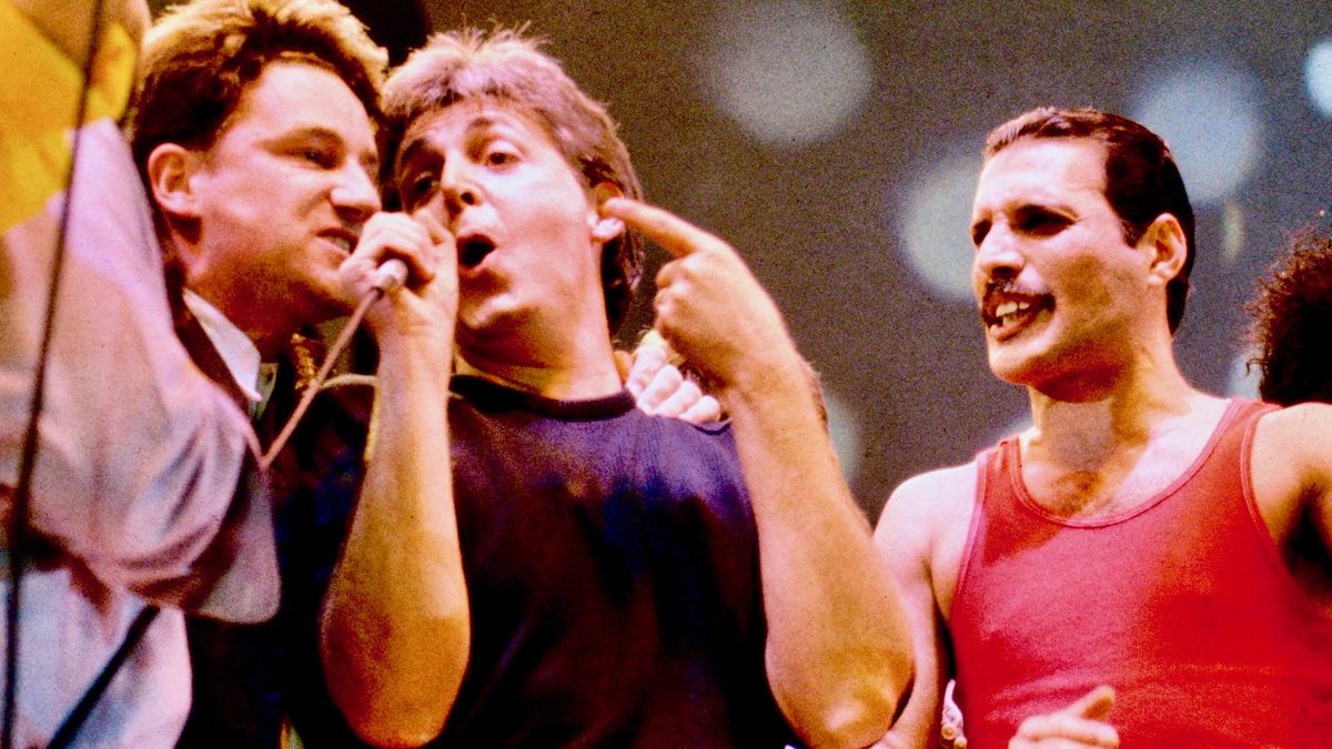 View of musicians including, from third left, Bono, Paul McCartney, and Freddie Mercury as they perform onstage during the Live Aid benefit concert, Wembley Stadium, London, 7/13/1985