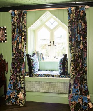 Green painted living room with window seat, floral patterned curtains, matching cushions and seat pad on window seat