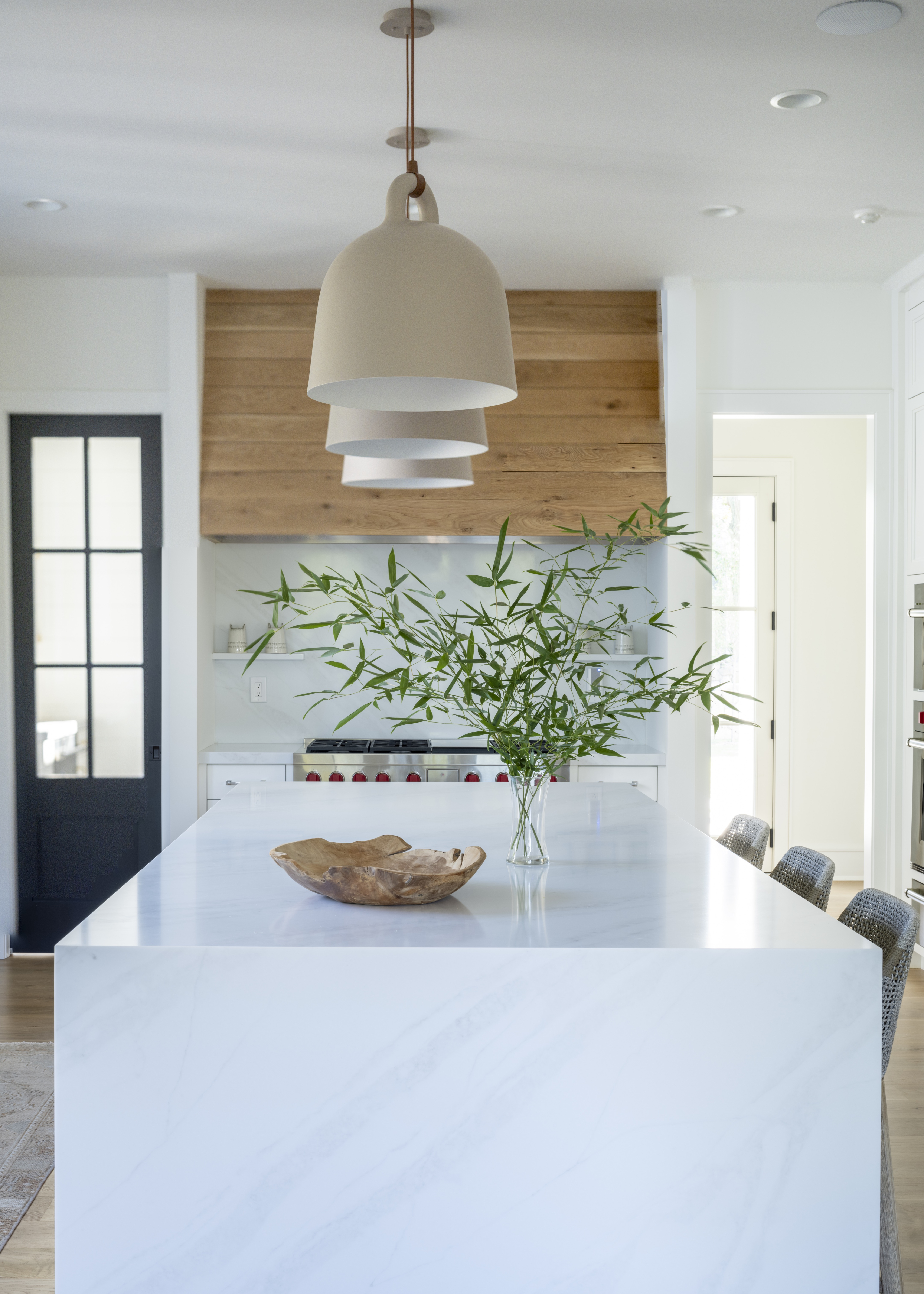 white kitchen with three pendants over an island and recessed spotlights
